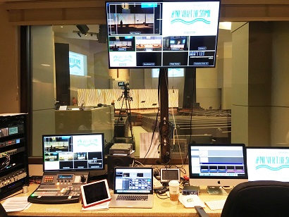 Interior of a control room with multiple computer screens displaying video feeds and editing controls